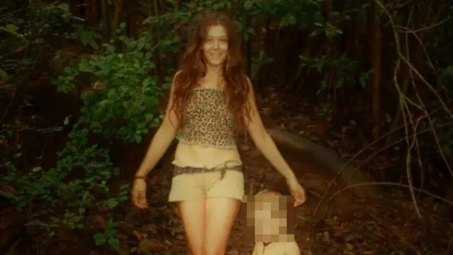 Nina Kutina kameraya gülümsəyir, yanında balaca bir uşaq görünür. Uşağın üzü bağlıdır.