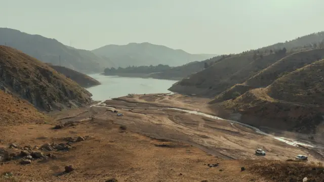 Latyan Barajı gölünün ortasında dar bir su alanı kalmış; çevresindeki geniş kısımlar tamamen kurumuş durumda.